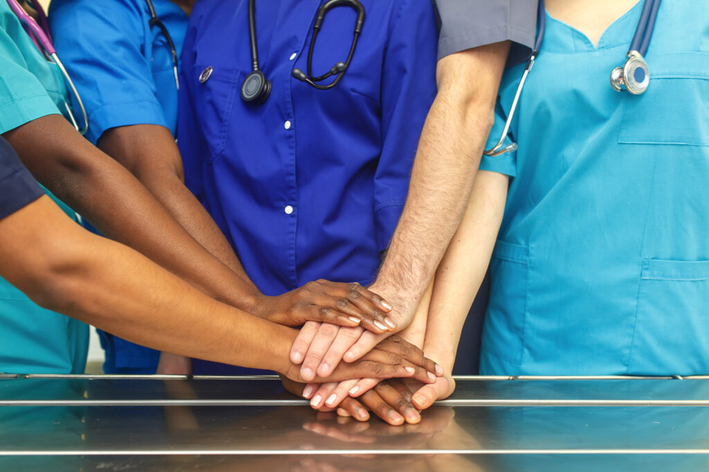 Who We Are - View Of Medical Team Stacking Hands Together in Solidarity